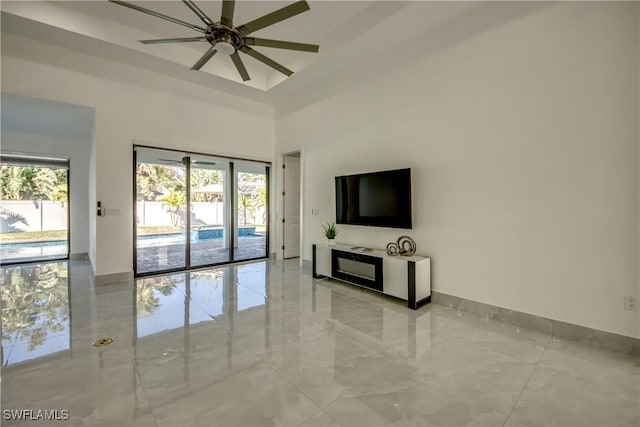 unfurnished living room featuring a towering ceiling and ceiling fan