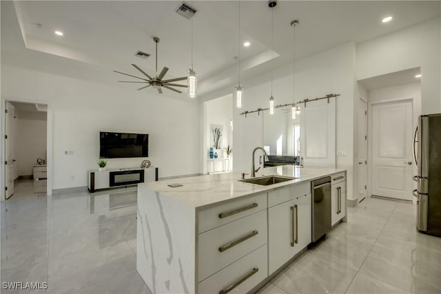 kitchen featuring sink, white cabinetry, stainless steel appliances, a barn door, and a kitchen island with sink