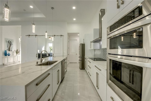 kitchen with sink, stainless steel appliances, white cabinets, decorative light fixtures, and a barn door