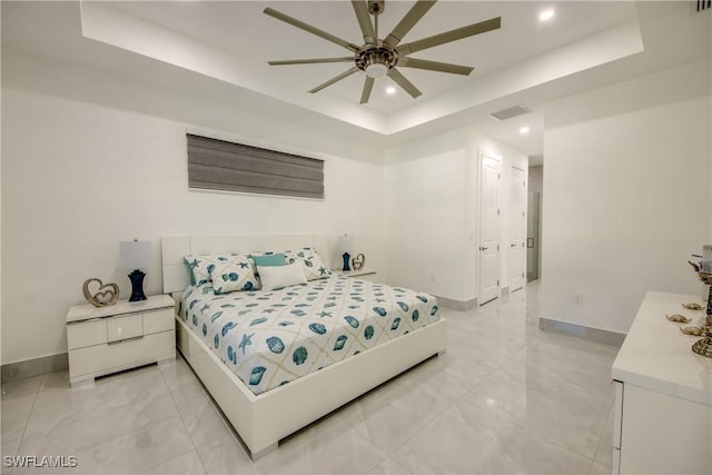 bedroom with ceiling fan and a tray ceiling