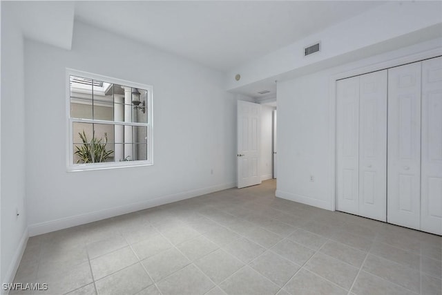 unfurnished bedroom featuring light tile patterned flooring and a closet