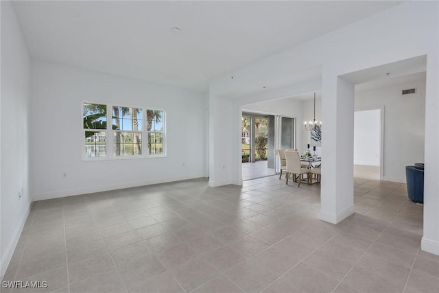 tiled empty room with an inviting chandelier