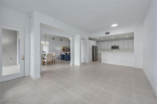 unfurnished living room featuring an inviting chandelier and light tile patterned floors