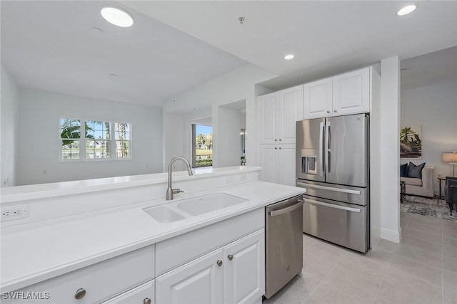 kitchen with appliances with stainless steel finishes, sink, light tile patterned floors, and white cabinets