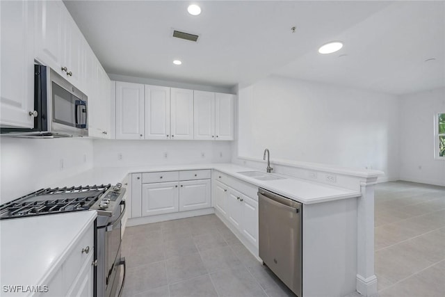 kitchen with sink, stainless steel appliances, kitchen peninsula, and white cabinets