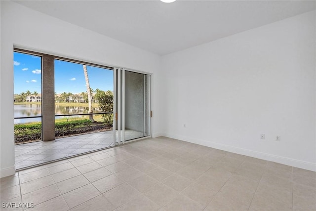 tiled spare room featuring a water view