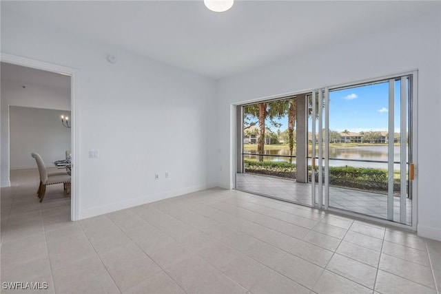 tiled empty room featuring a water view and a chandelier