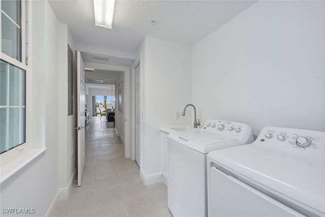 laundry room featuring washer and dryer, light tile patterned flooring, and sink