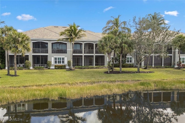 back of house with a water view and a yard