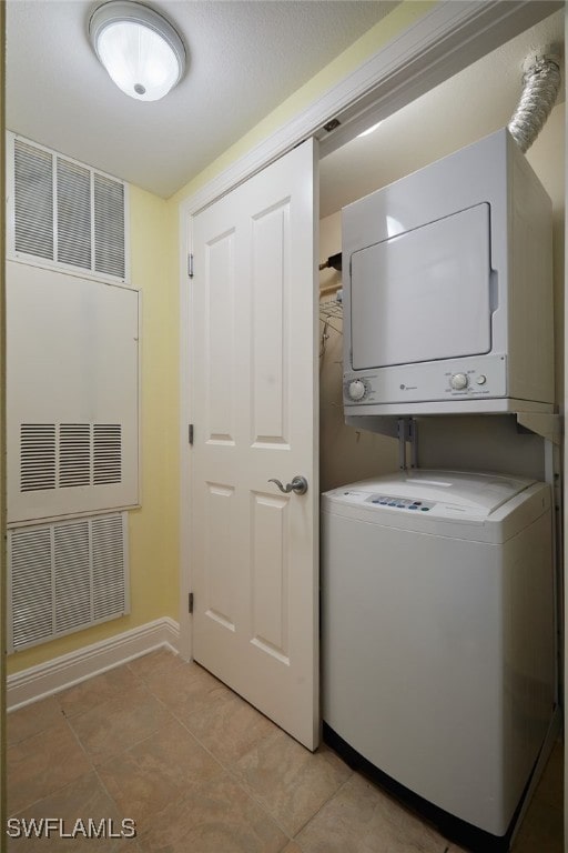 laundry area with visible vents, laundry area, stacked washer / drying machine, and baseboards