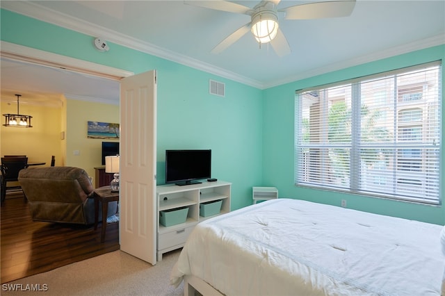 bedroom with crown molding, visible vents, a ceiling fan, and light wood-style flooring