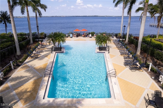 pool featuring a water view, a patio area, and fence