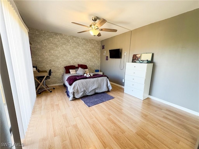 bedroom with ceiling fan, brick wall, and light hardwood / wood-style floors