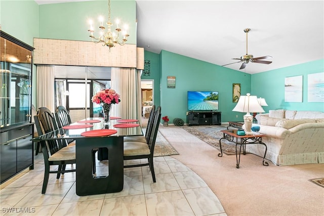 carpeted dining area with ceiling fan with notable chandelier and high vaulted ceiling