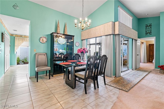 dining room featuring an inviting chandelier, a towering ceiling, and carpet flooring