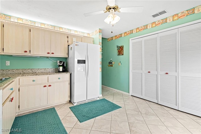 kitchen featuring white fridge with ice dispenser, light brown cabinets, ceiling fan, and light tile patterned floors