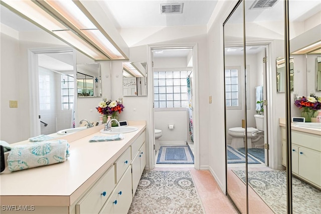 bathroom featuring a healthy amount of sunlight, toilet, and vanity