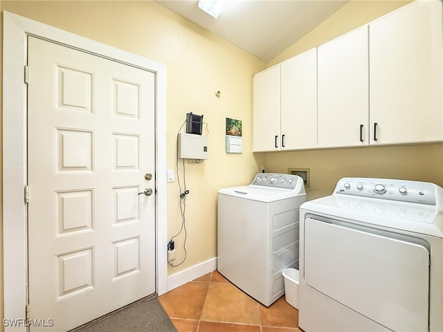 clothes washing area with washing machine and clothes dryer, light tile patterned floors, and cabinets