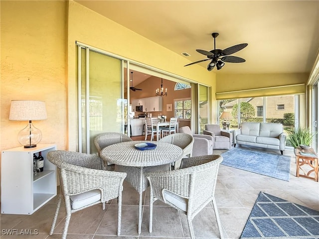 sunroom with ceiling fan with notable chandelier and lofted ceiling