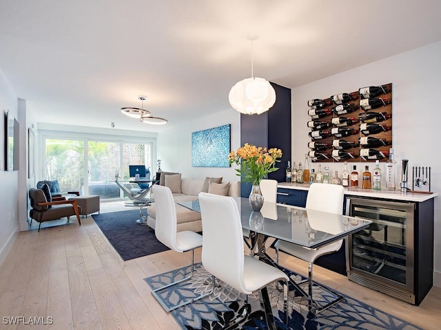 dining area featuring beverage cooler, a dry bar, and light wood finished floors