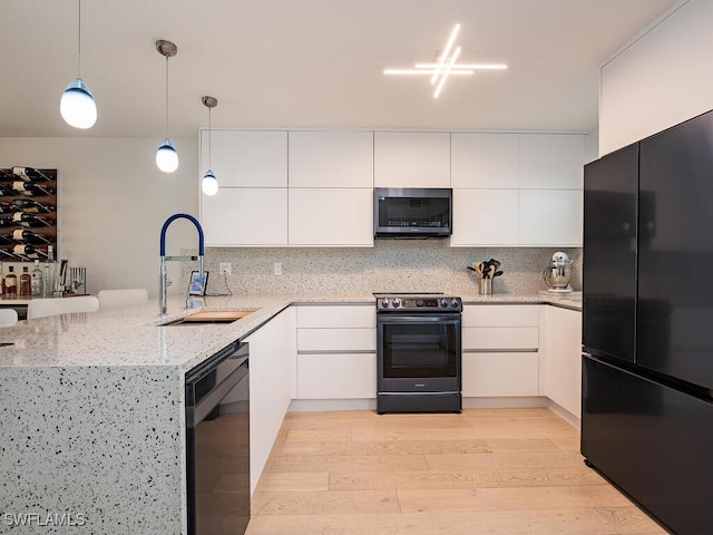 kitchen featuring a peninsula, a sink, white cabinetry, black appliances, and decorative light fixtures