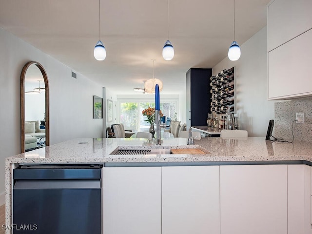 kitchen featuring open floor plan, pendant lighting, light stone countertops, and white cabinets