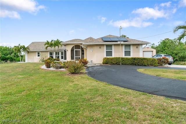 ranch-style house featuring a front yard, roof mounted solar panels, driveway, and stucco siding