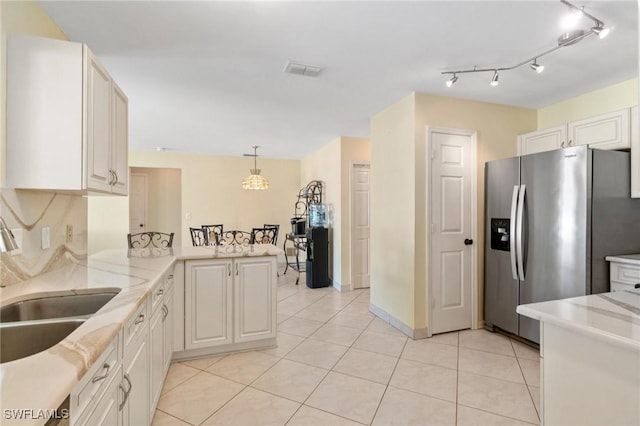 kitchen featuring tasteful backsplash, stainless steel fridge with ice dispenser, a peninsula, a sink, and light tile patterned flooring