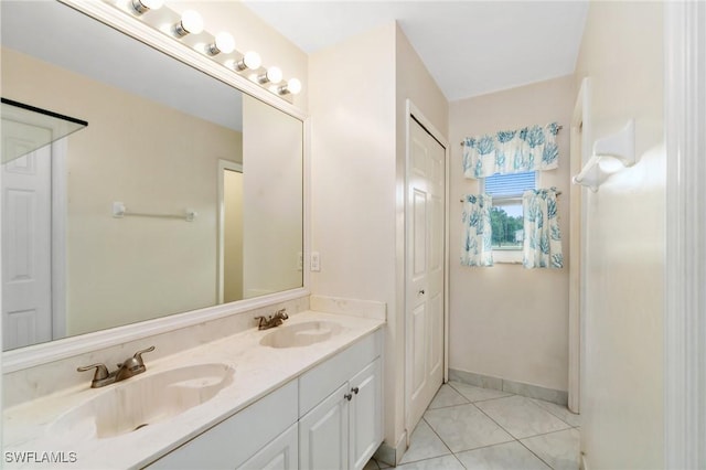 full bath with baseboards, double vanity, a sink, and tile patterned floors