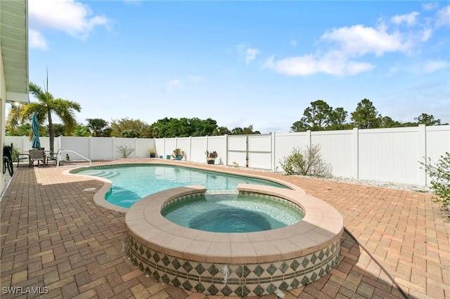 view of pool featuring a fenced backyard, a pool with connected hot tub, and a patio