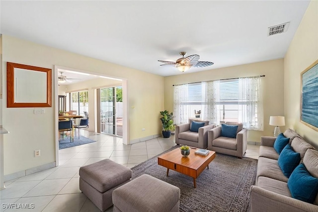 living area with light tile patterned floors, ceiling fan, visible vents, and baseboards