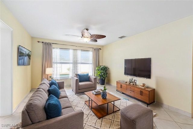 living area with light tile patterned floors, ceiling fan, visible vents, and baseboards