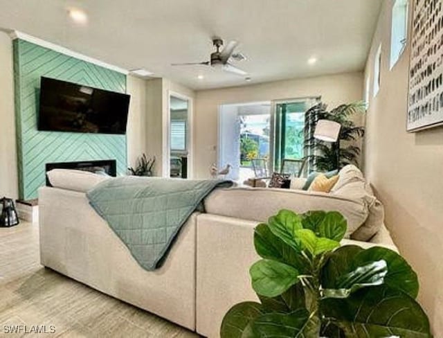 living room featuring wood-type flooring, a large fireplace, and ceiling fan