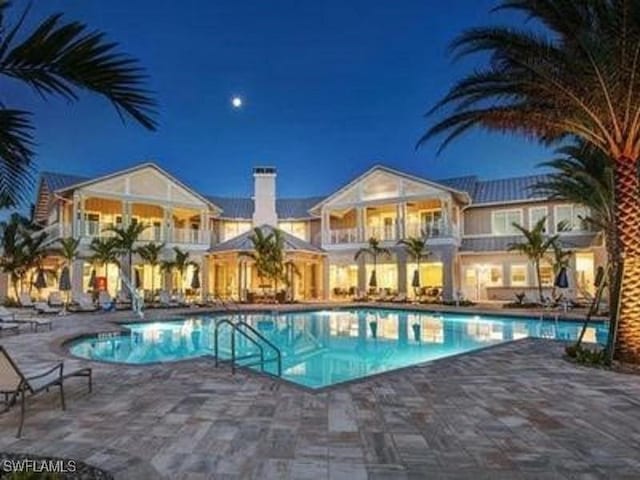 pool at night featuring a patio