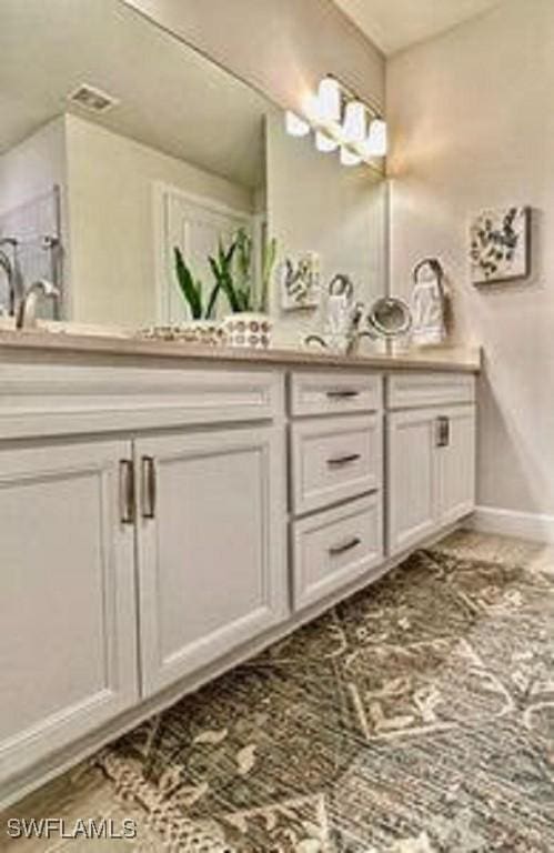 full bath with double vanity, a sink, visible vents, and baseboards