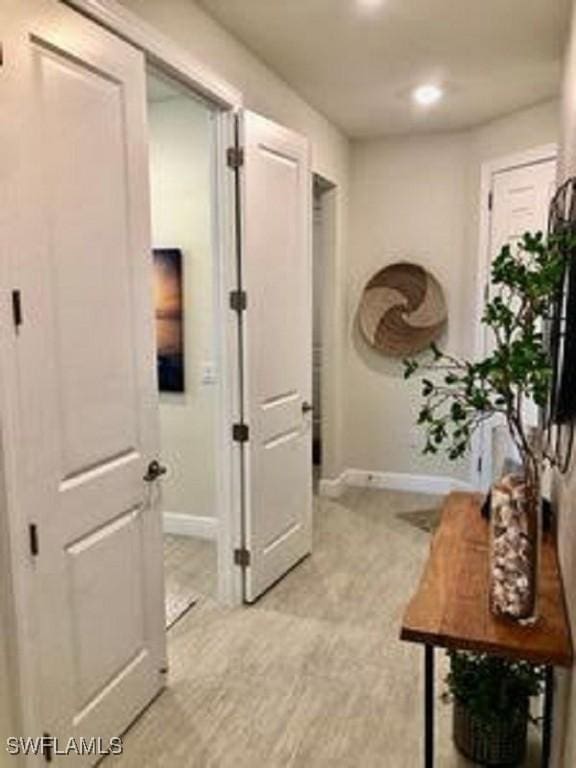 corridor featuring light wood-type flooring and baseboards