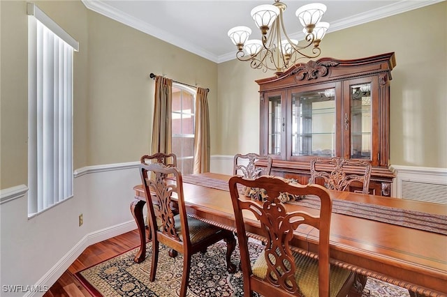 dining space with hardwood / wood-style flooring, ornamental molding, and a notable chandelier