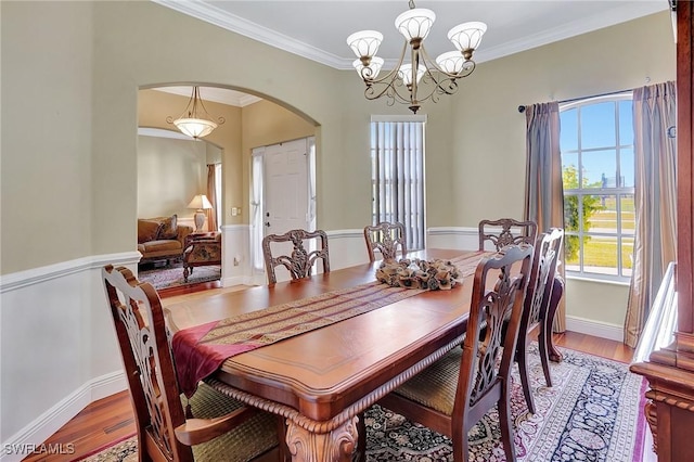 dining room with hardwood / wood-style flooring, crown molding, and a chandelier