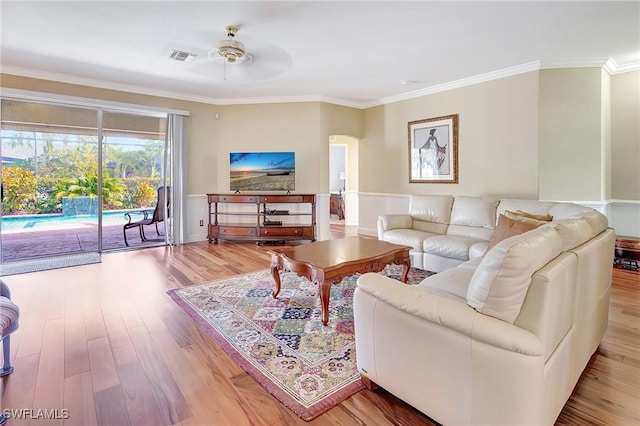 living room with crown molding, ceiling fan, and light wood-type flooring