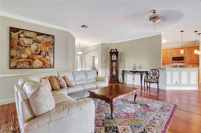 living room with crown molding, hardwood / wood-style floors, and ceiling fan