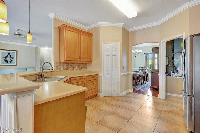 kitchen with stainless steel refrigerator, sink, decorative backsplash, ornamental molding, and light tile patterned floors