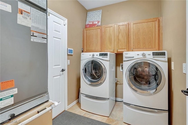 laundry area featuring cabinets, light tile patterned floors, and washing machine and clothes dryer