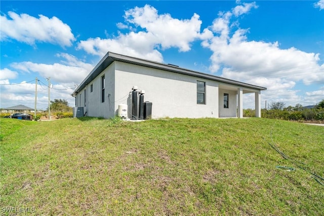 rear view of property featuring a yard and central AC