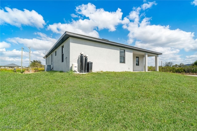 back of property featuring a yard and central AC