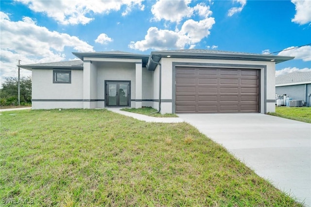 view of front of property with a garage, a front yard, and central air condition unit