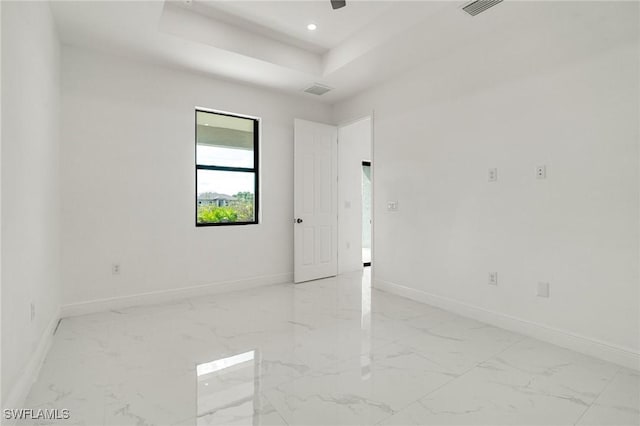 spare room with ceiling fan and a tray ceiling