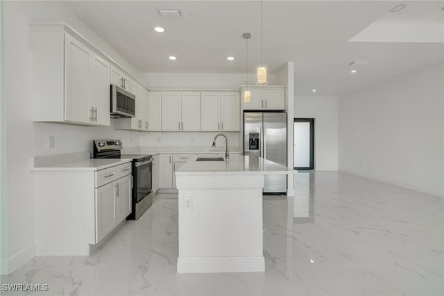 kitchen featuring sink, appliances with stainless steel finishes, a kitchen island with sink, white cabinets, and decorative light fixtures