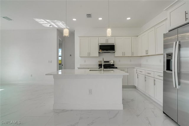 kitchen with sink, an island with sink, pendant lighting, stainless steel appliances, and white cabinets