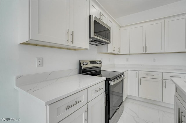 kitchen with appliances with stainless steel finishes, white cabinets, and light stone counters