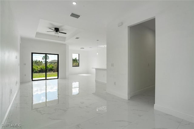 unfurnished room with ceiling fan and a tray ceiling